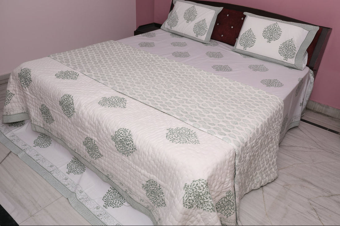 Bed with a floral patterned quilt and pillows in a room with pink walls.