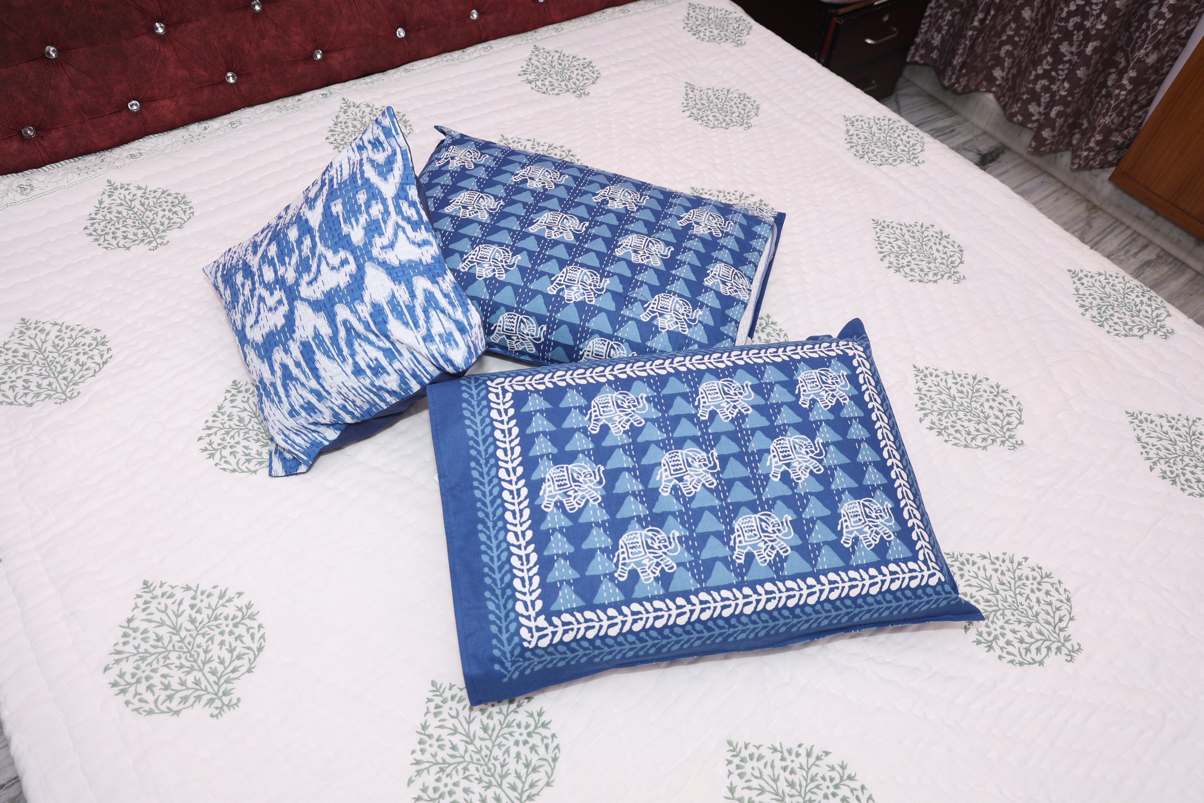 Verdant floral hand-block quilt styled on bed showing green botanical print drape