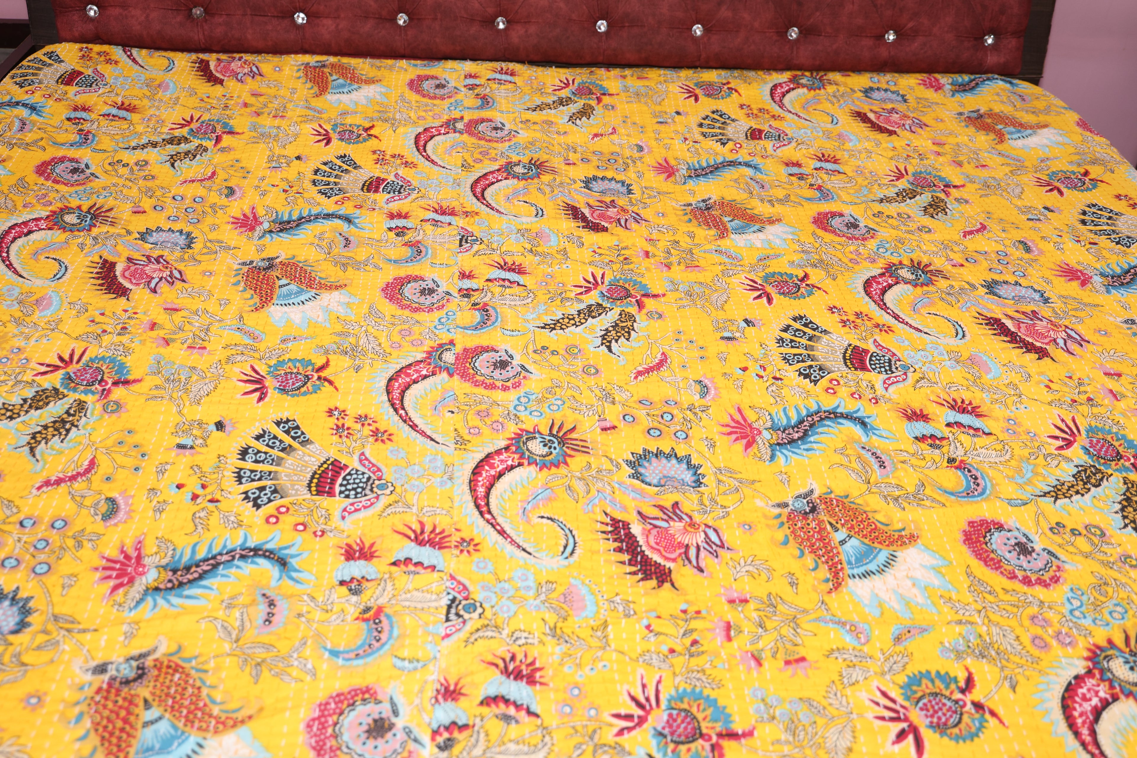 Saffron paisley kantha throw folded on wooden surface showing artisan stitching