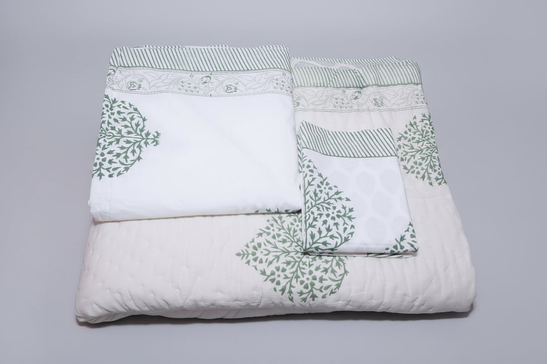 Bed with a floral patterned quilt and pillows in a room with pink walls.