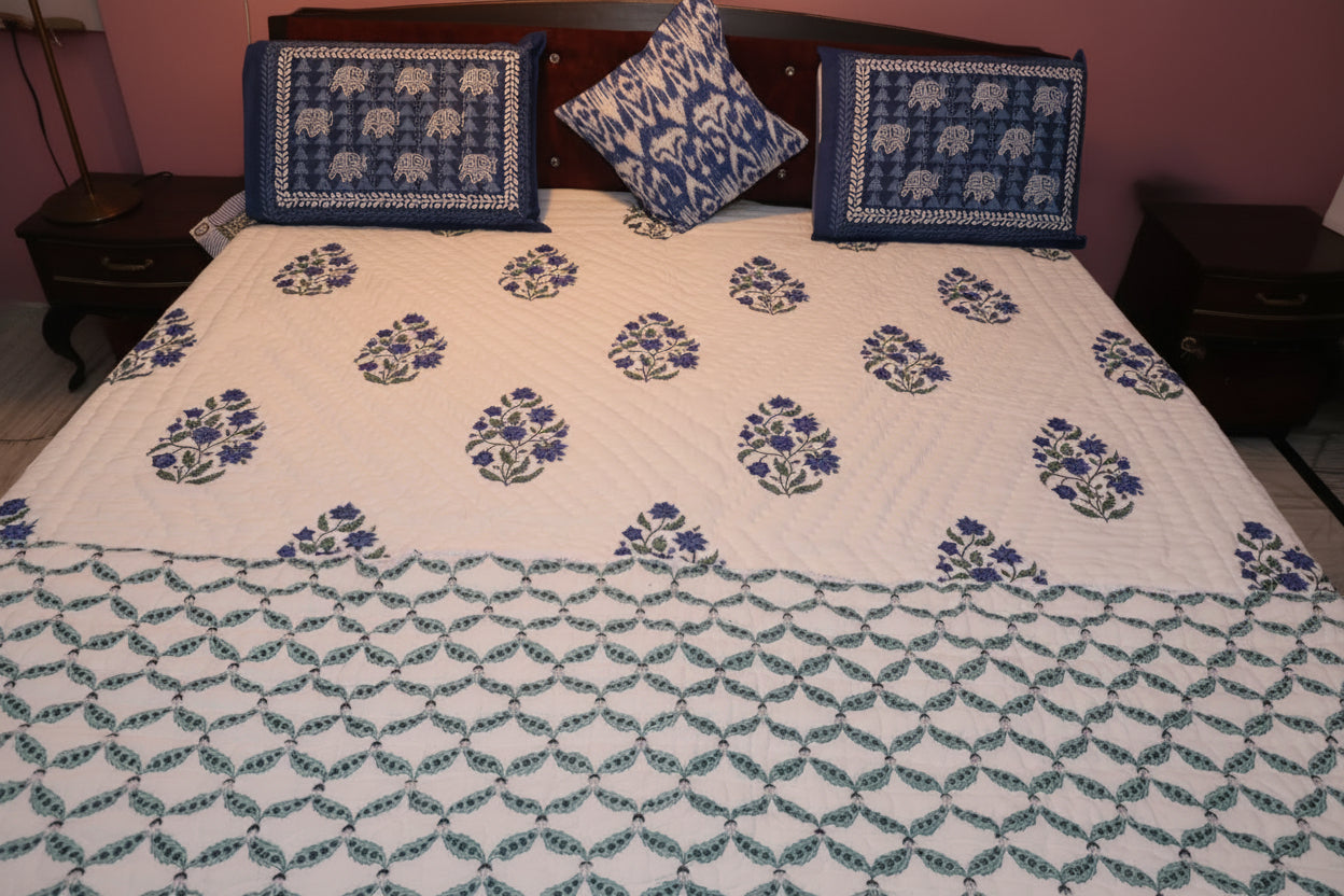 Bed with floral patterned quilt and matching pillows showing both the sides of the quilt