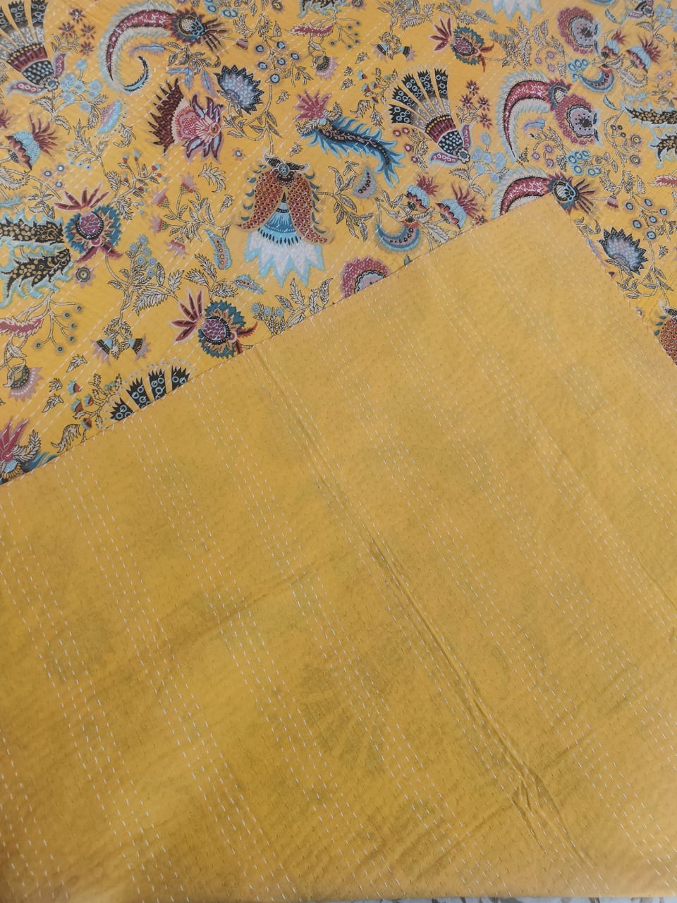 Detail of hand-stitched kantha running stitch on saffron paisley cotton throw