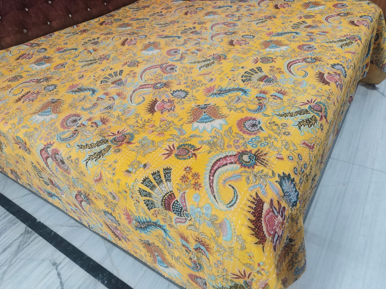 Close-up of saffron paisley and peacock hand-stitched kantha pattern