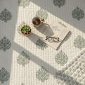 Verdant floral hand-block quilt flat lay showing dense green botanical block print pattern