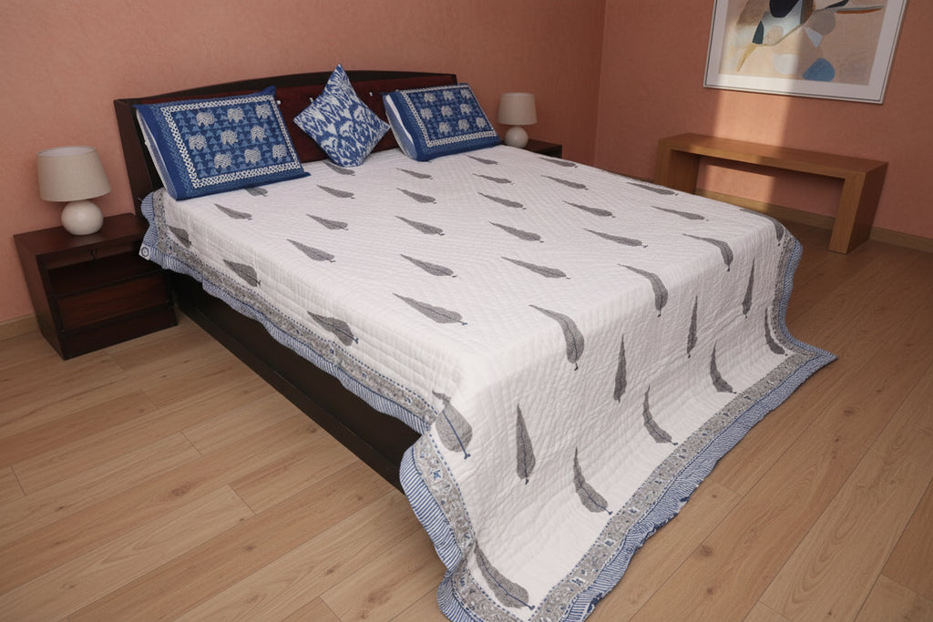 Bed with a white quilt and blue pillows in a bedroom setting.