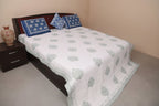Bed with white quilt and blue patterned pillows
