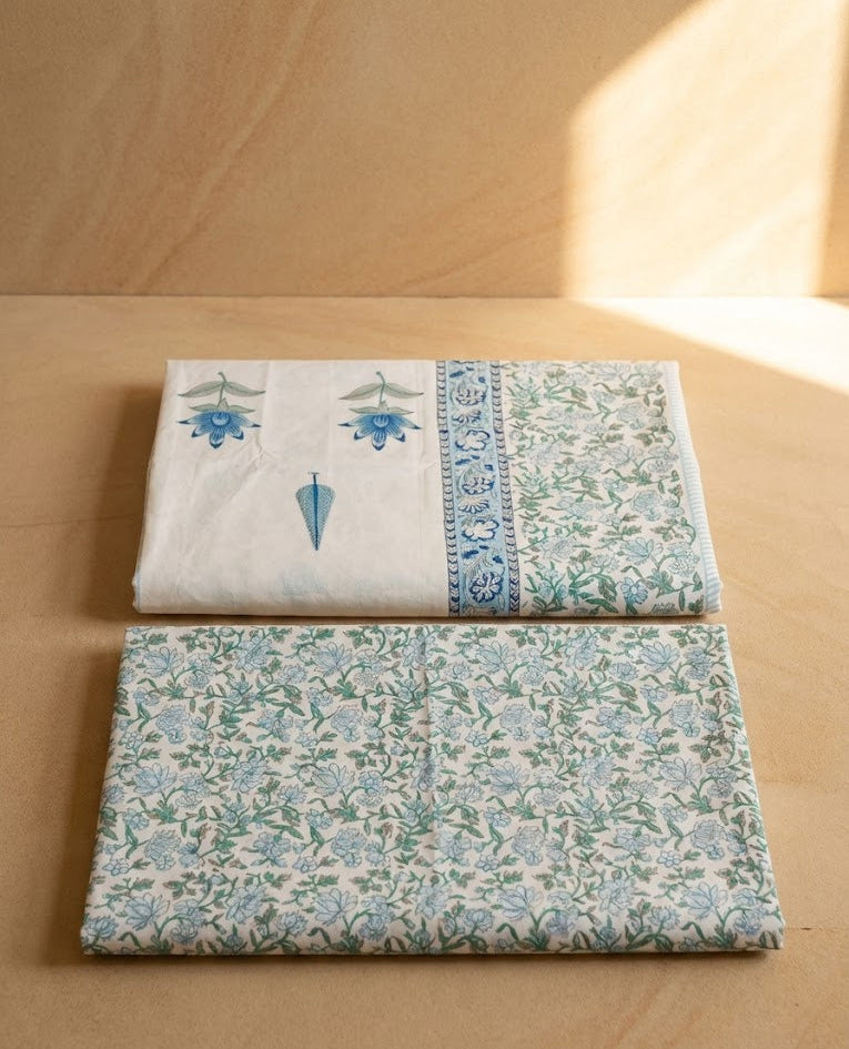 Two folded fabric swatches with floral patterns on a wooden surface